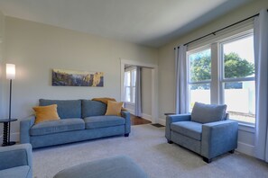 A living room with a sofa, armchair, and a painting on the wall. - Charming Home 1/2 mi Walk to Downtown Lee's Summit (Lee's Summit)