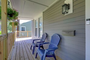 A wooden porch with two Adirondack chairs, a mailbox, and a hanging flower basket. - Charming Home 1/2 mi Walk to Downtown Lee's Summit (Lee's Summit)