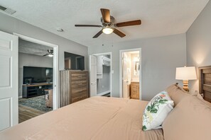 Ein Schlafzimmer mit Bett, Deckenventilator, Fernseher und Kommode.