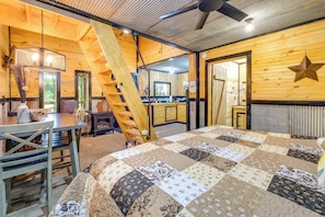 A wooden interior with a bed, a table, chairs, a staircase, and a kitchen area. - Ozark Escape! Cabin w/ On-site Hiking & Fishing (Stella)