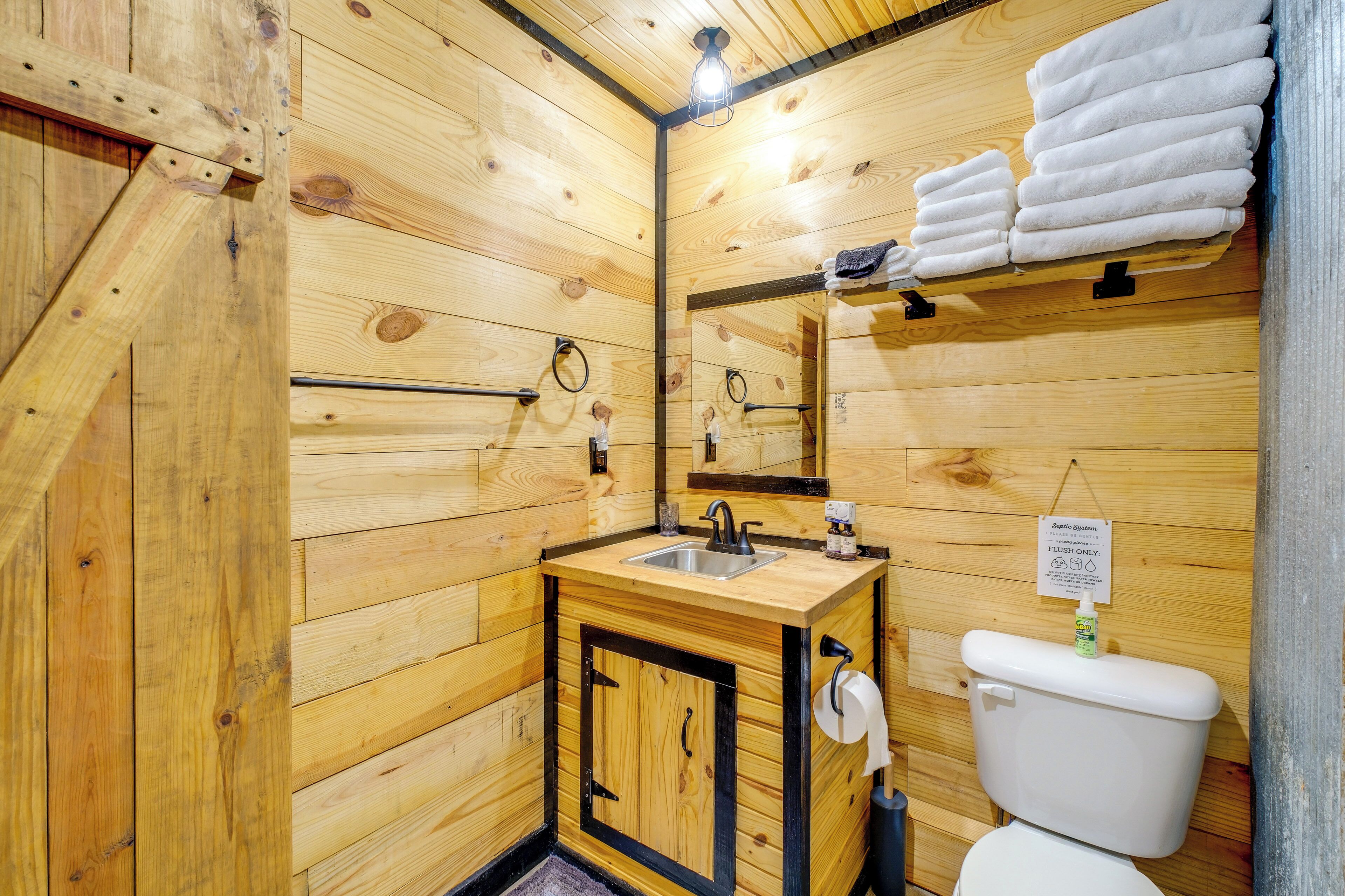 Een houten badkamer in chaletstijl, met een wastafel, toilet en handdoekrek.
