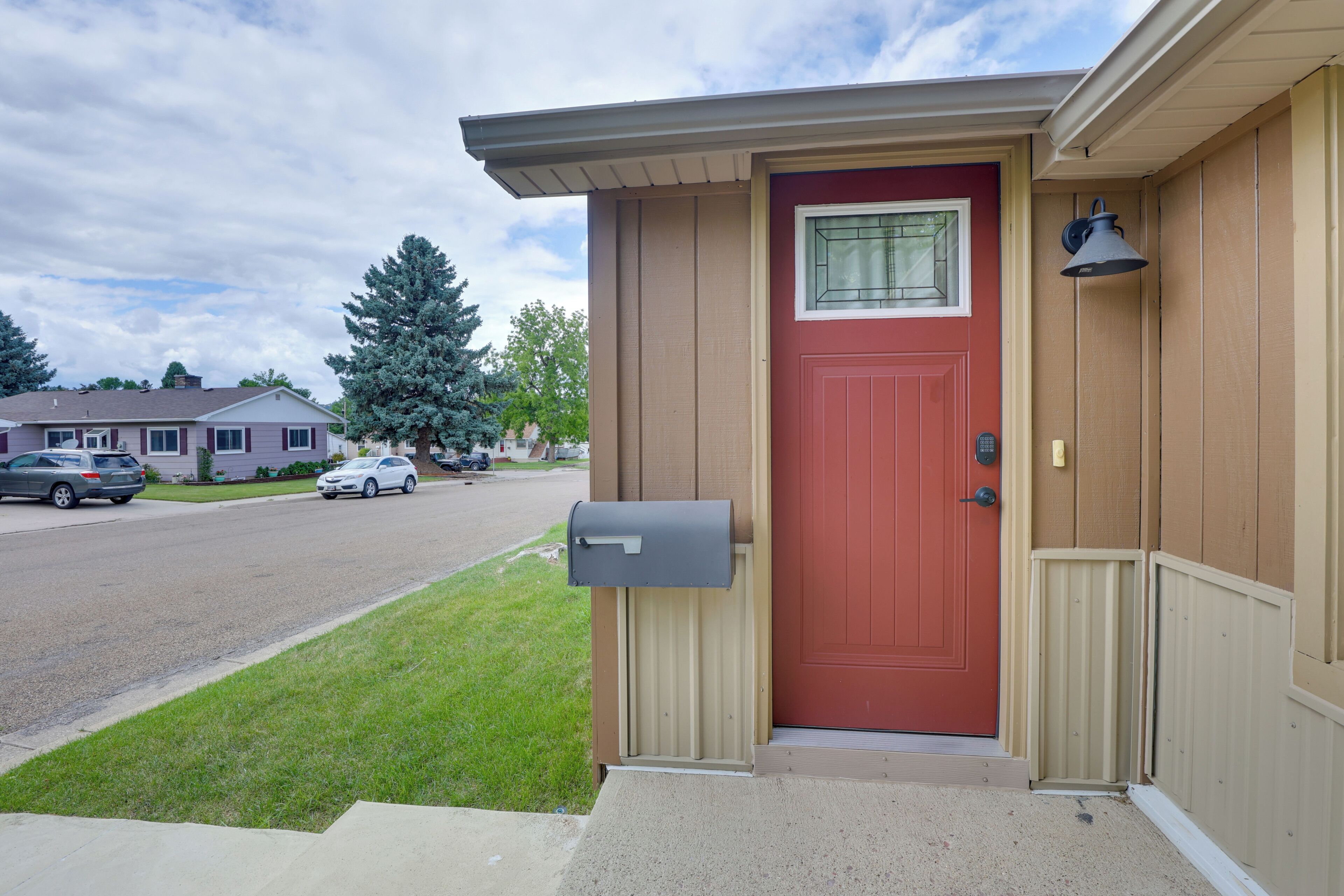 A residential house with a red door, a mailbox, and a small porch.