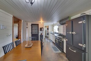 A kitchen with a wooden dining table, chairs, a stove, oven, and a large refrigerator. - Black Hills Basecamp: Sturgis Home w/ Yard! (Sturgis)