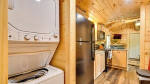 A compact kitchen with wooden cabinets, a stainless steel refrigerator, and a washing machine.