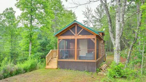 A cabin with a wooden exterior, large windows, and a covered porch.