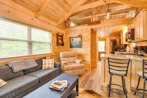A cozy cabin interior with a sofa, armchair, and bar area.