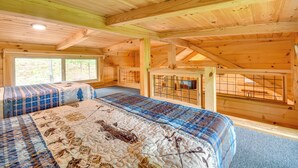 A wooden cabin interior with a bed, a window, and a fenced area.