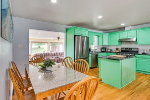 A modern kitchen with green cabinets, stainless steel appliances, and a dining area with wooden chairs and a granite table. - 5 Mi to Dtwn Harrisburg! Retreat w/ Spacious Yard (Harrisburg)
