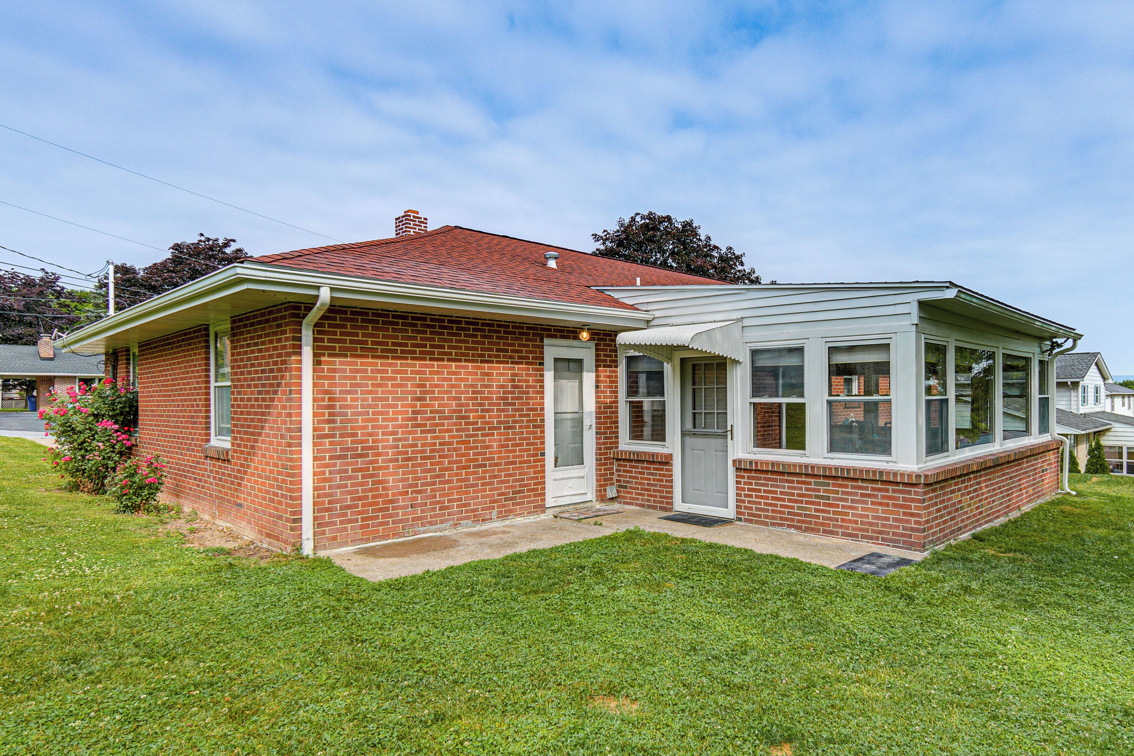 A single-story brick house with a covered porch, a front door, and a small front yard.