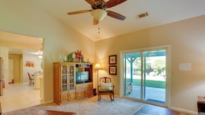 A living room with a ceiling fan, a television, a wooden cabinet, a chair, a coffee table, and a sliding glass door leading to an outdoor area. - 5 Mi to Sundial Bridge & River! Pet-friendly Haven (Redding)