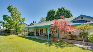 A house with a covered porch, a lawn, and a tree with red leaves. - 5 Mi to Sundial Bridge & River! Pet-friendly Haven (Redding)