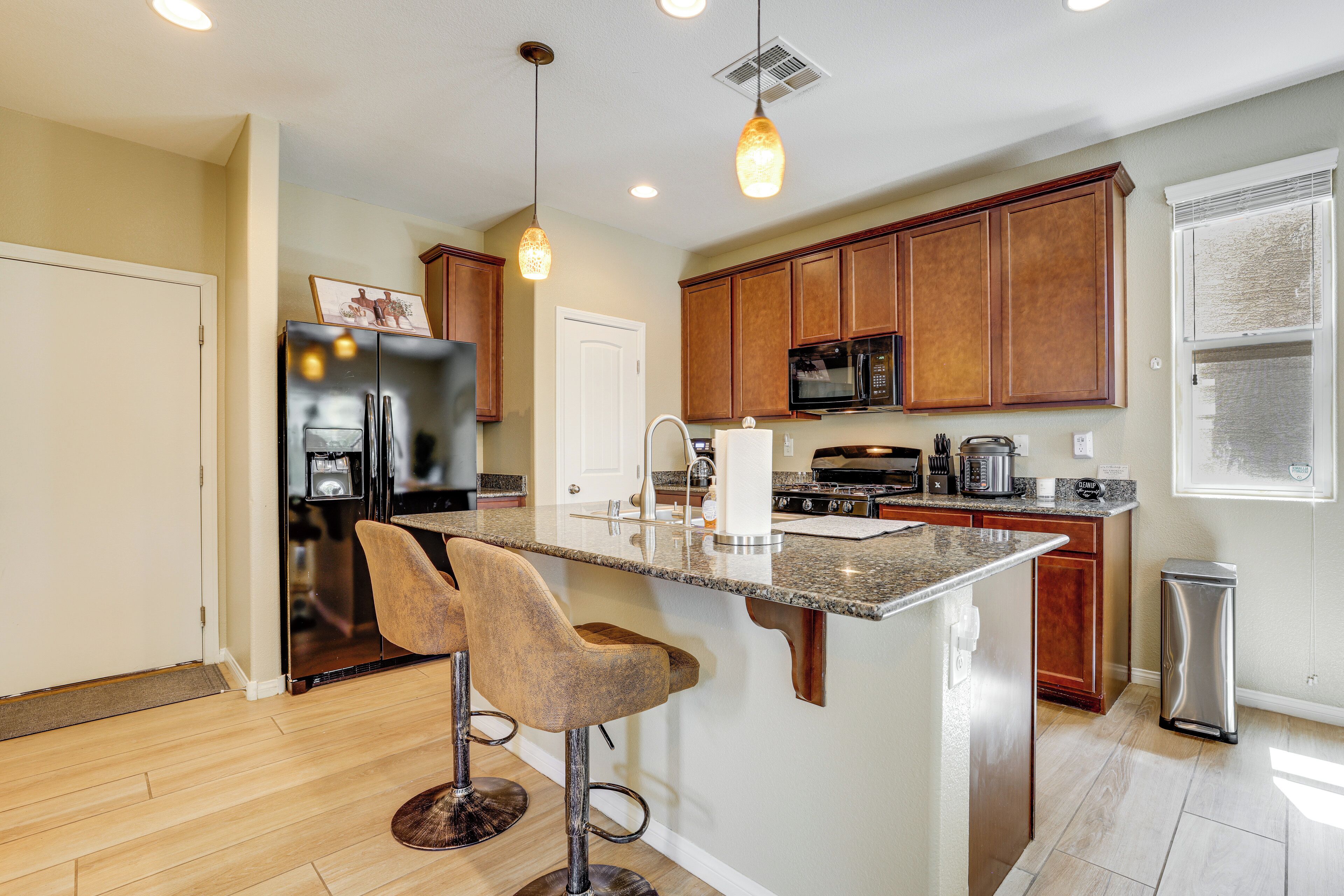A kitchen with wooden cabinets, a stainless steel refrigerator, a microwave, and a granite countertop.