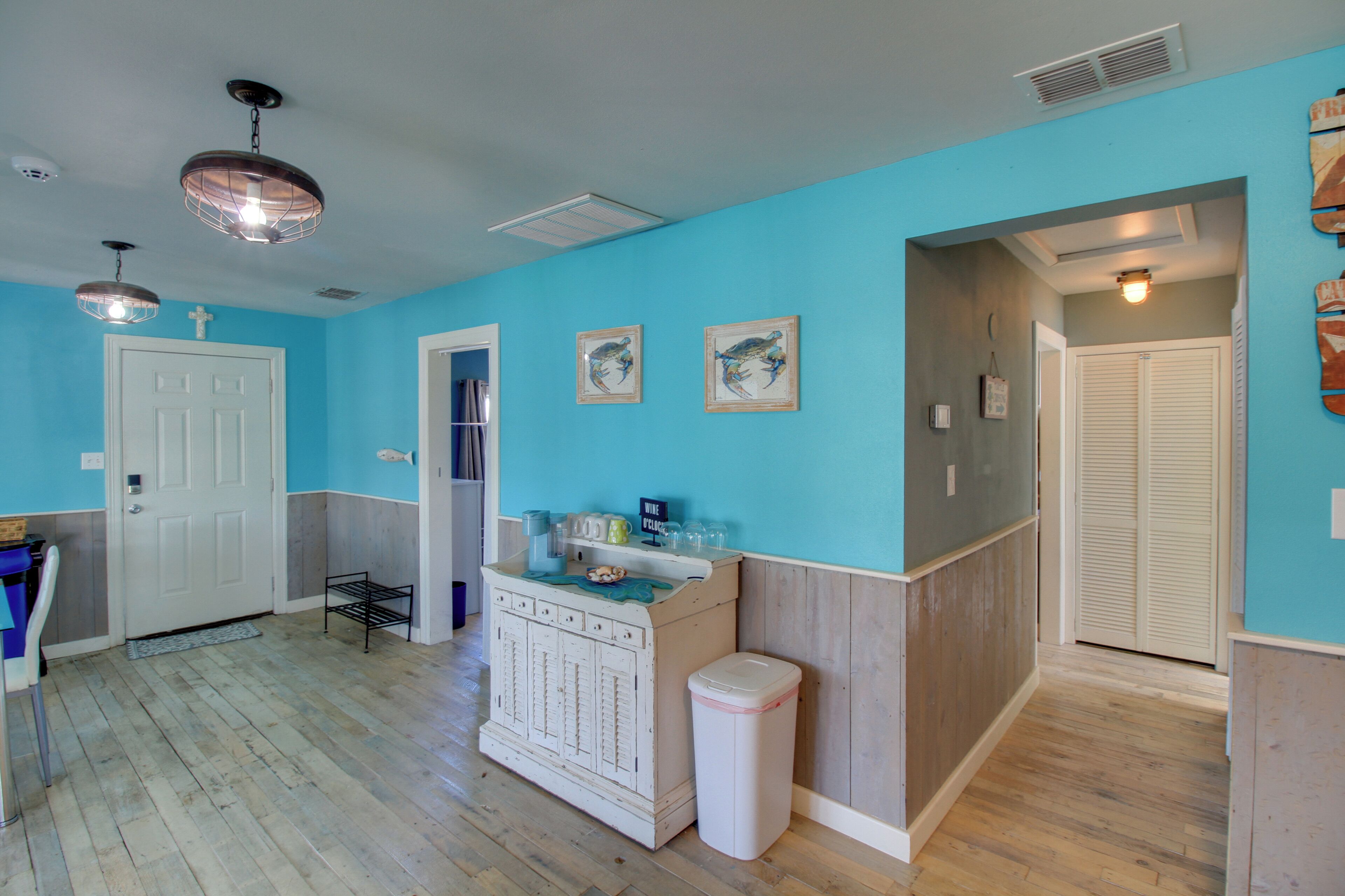 A room with a wooden floor, a white door, a white cabinet, and a trash can.