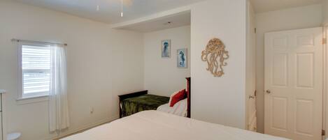 A bedroom with a bed, a ceiling fan, a window with blinds, and a door.