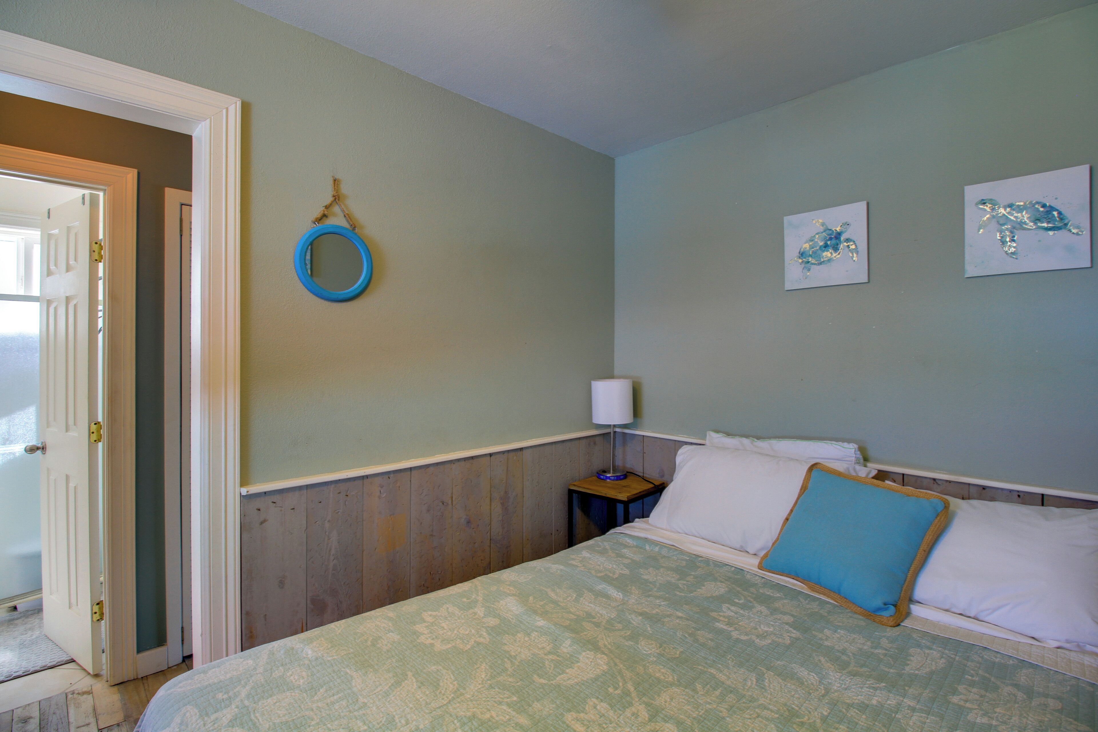 Ein Schlafzimmer mit einem Bett, einem Nachttisch, einem Wandspiegel und zwei Wandbildern.