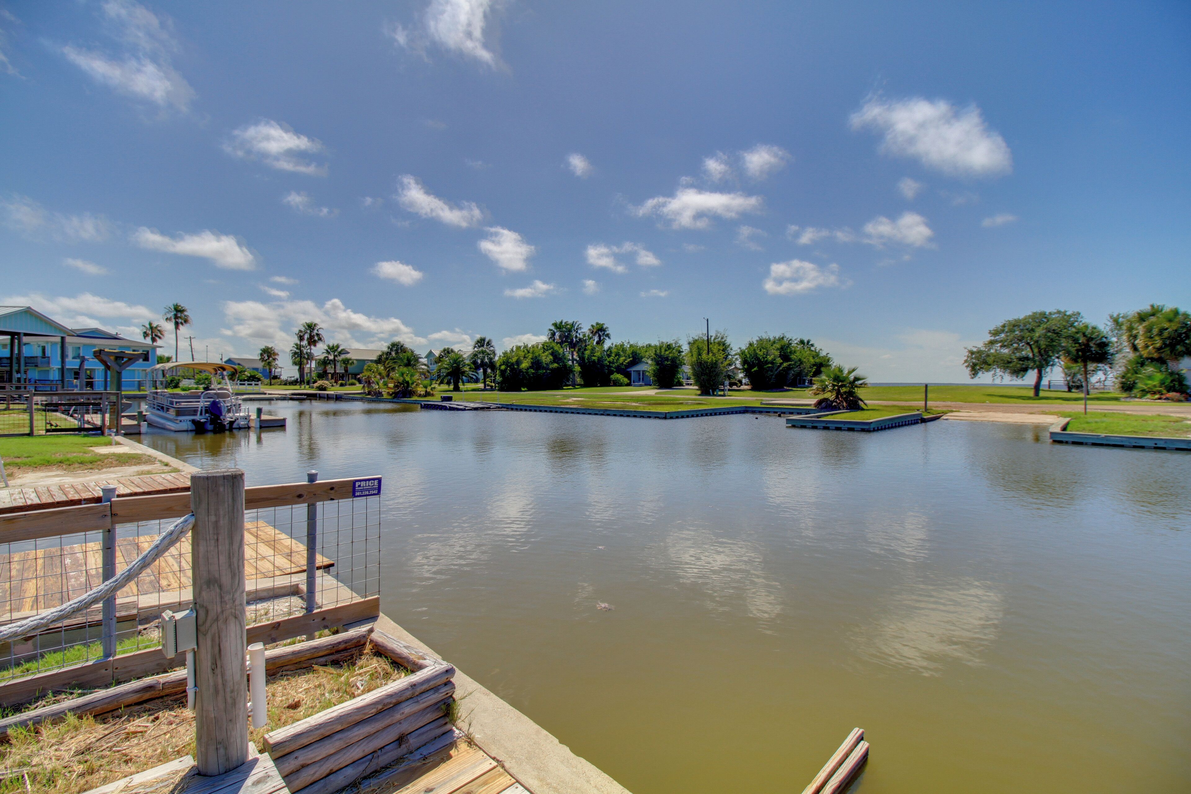 A calm lake with a dock, a boat, and a small building in the background.