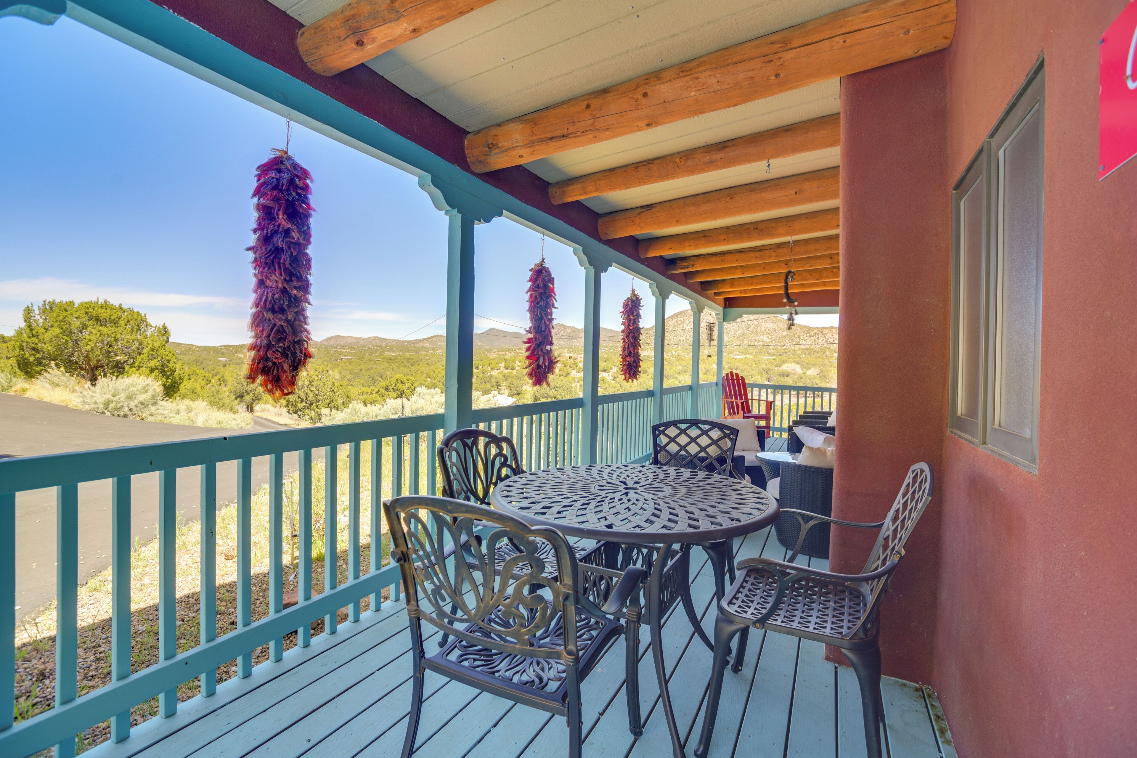 A covered outdoor seating area with a table and chairs, a railing, and hanging decorations.