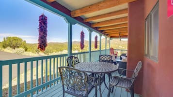 A covered outdoor seating area with a table and chairs, a railing, and hanging decorations.