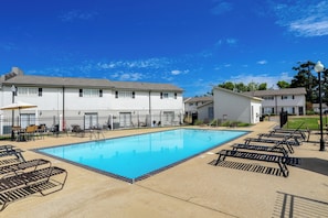 A swimming pool with lounge chairs, a covered seating area, and a fenced poolside. - Walk to Stadium and Campus! Cozy Townhome w/ Pool (Oxford)