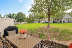 An outdoor patio with a table, chairs, and a flower vase.