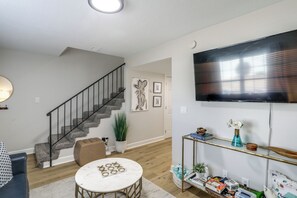 A living room with a staircase, a flat-screen TV, a round coffee table, and a console table with decorative items.