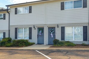 A two-story building with a brick facade, two front doors, and a small front yard with bushes.