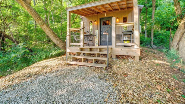 A wooden cabin with a porch, a door, and a window. - Wren's Nest Cabin: Missouri Ozarks Getaway! (Stella)