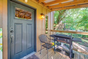 A wooden deck with a grill, a door with a window, and a chair.
