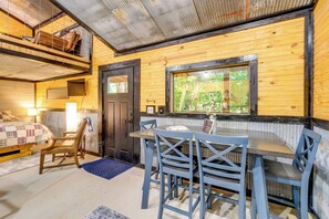 L’intérieur d’une cabane comprend un coin repas, un lit et une fenêtre donnant sur un paysage verdoyant.