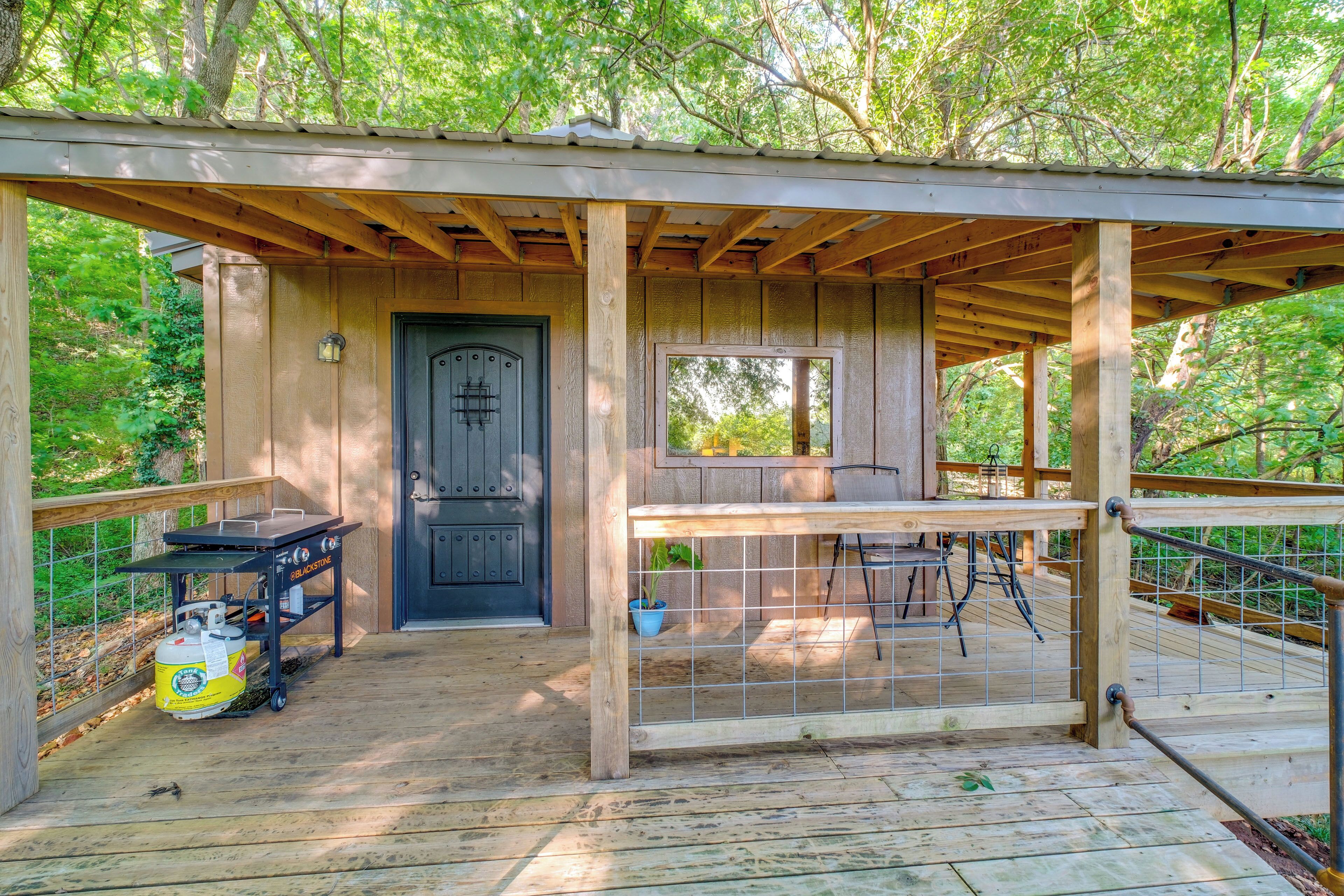 A wooden deck with a covered area, a door, and a grill cart.