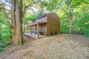 A wooden cabin with a covered porch, surrounded by trees. - On-site Trails & Fishing Pond: Rustic Ozark Cabin (Stella)