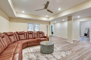 A spacious living room with a leather sectional sofa, a round coffee table, and a ceiling fan. - 3 Mi to Dtwn Douglasville! Apt w/ Yard & Patio (Douglasville)