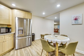 A kitchen with stainless steel appliances, wooden cabinets, and a dining area with a table and chairs. - 3 Mi to Dtwn Douglasville! Apt w/ Yard & Patio (Douglasville)