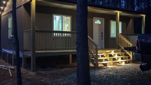 A cabin with a front porch, a staircase, and a vehicle parked outside. - Woodsy Cabot Escape in Arkansas Countryside! (Cabot)