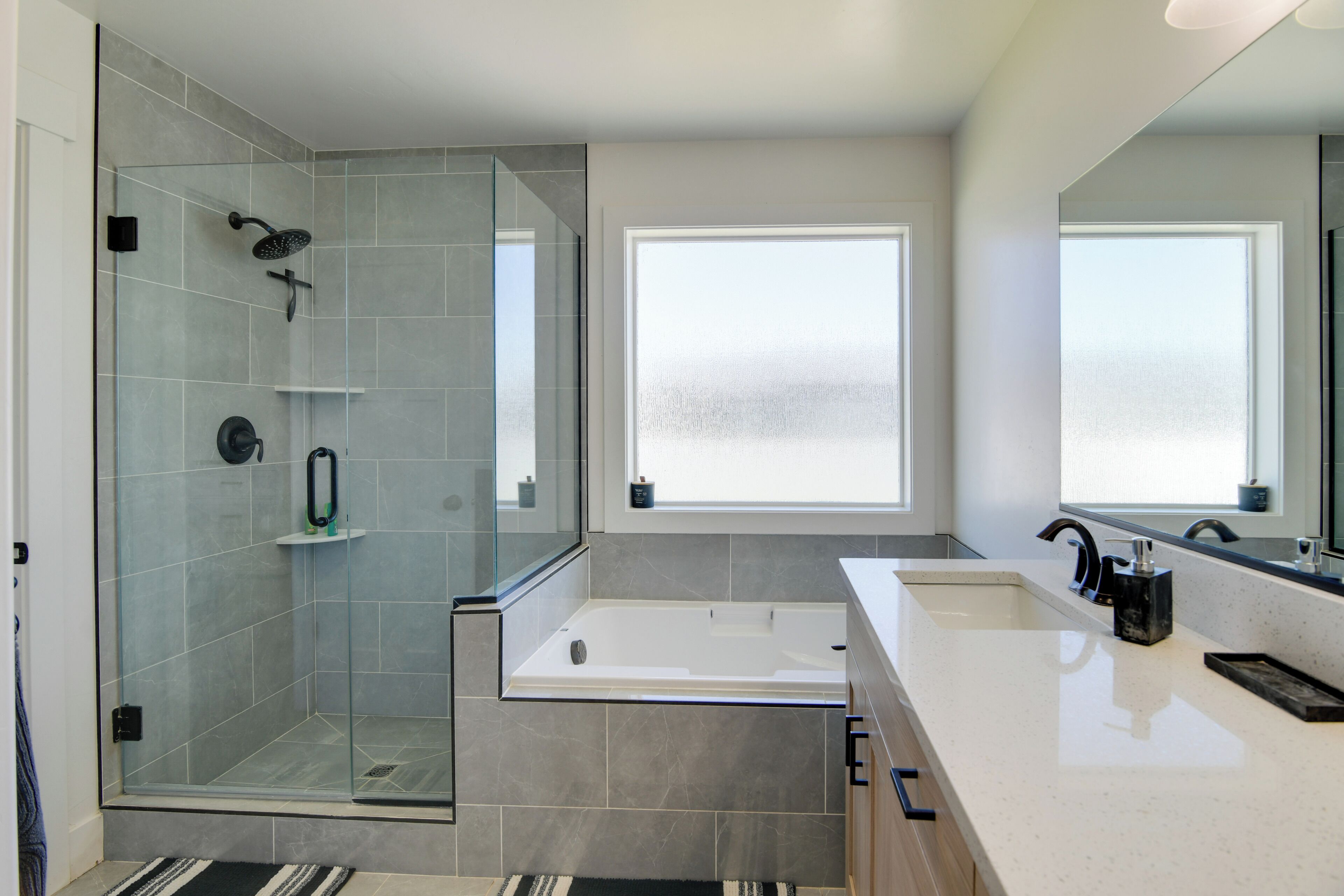 Une salle de bain moderne dotée d’une douche à parois de verre, d’une grande baignoire et d’un meuble-lavabo.