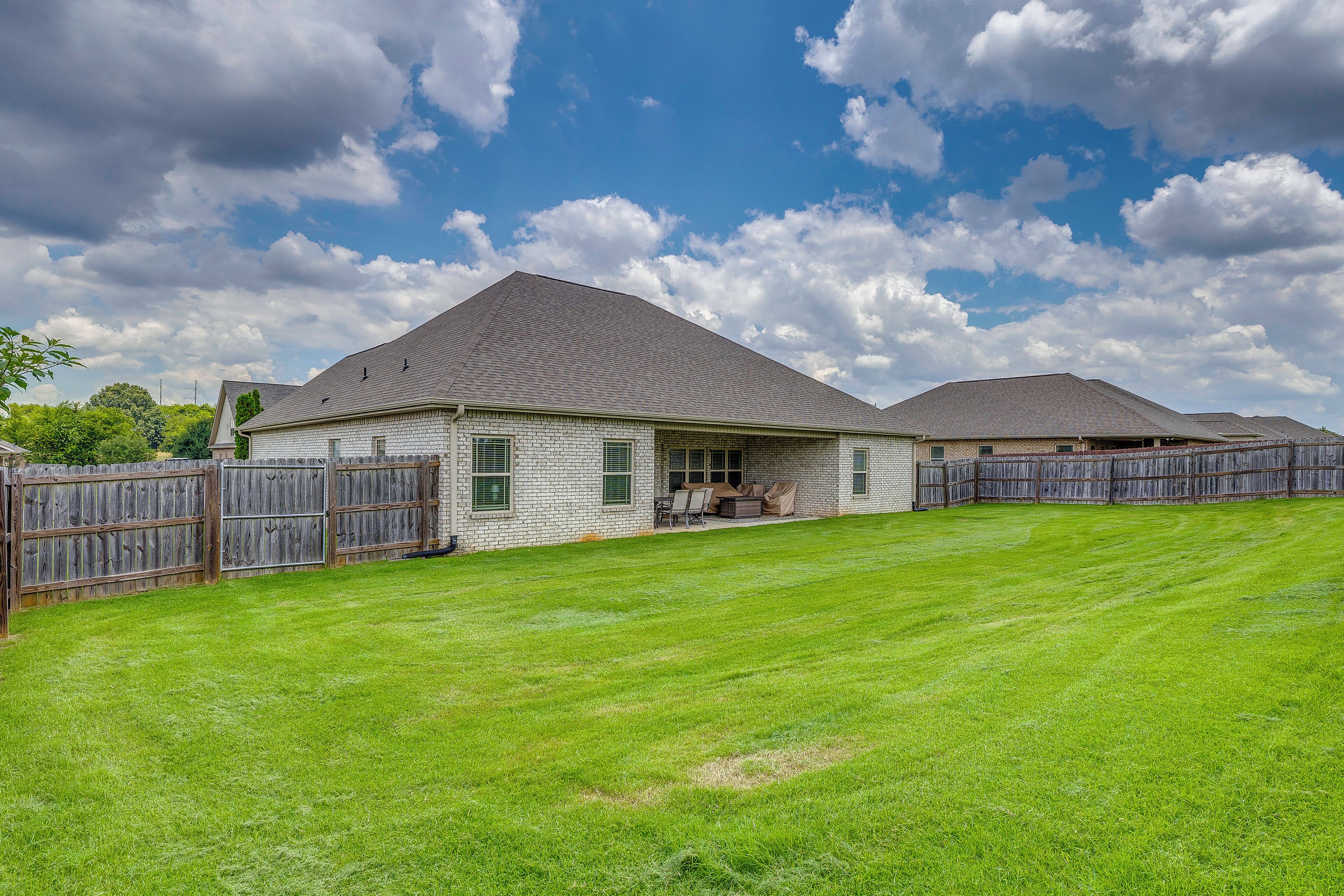 A residential property with a covered patio, a fenced yard, and a clear sky.