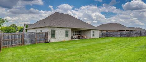 A residential property with a covered patio, a fenced yard, and a clear sky.