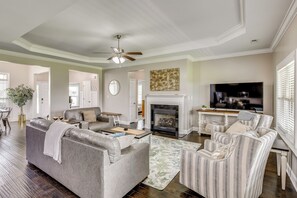 A living room with a sofa, armchair, fireplace, television, and a ceiling fan. - Spacious Meridianville Family Home w/ Patio (Meridianville)