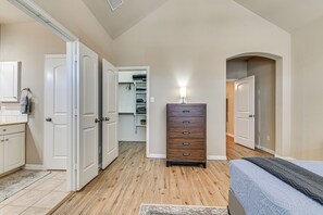 A bedroom with a bed, a dresser, a closet, and a bathroom with a sink and mirror. - Lewisville Home w/ Pool Access: Walkable Location (Lewisville)