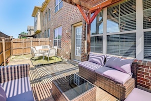 A patio with wicker furniture, a glass-top table, and a brick wall. - Lewisville Home w/ Pool Access: Walkable Location (Lewisville)