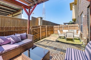 A backyard patio with a wicker sofa, a glass table, and a wooden fence. - Lewisville Home w/ Pool Access: Walkable Location (Lewisville)