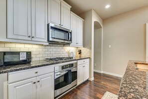 A kitchen with white cabinets, a microwave, stove, oven, and granite countertops. - Lewisville Home w/ Pool Access: Walkable Location (Lewisville)