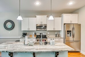 A modern kitchen with white cabinets, a central island, stainless steel appliances, and pendant lighting. - Stay & Play! Pinehurst Family & Group Golf Retreat (Pinehurst)