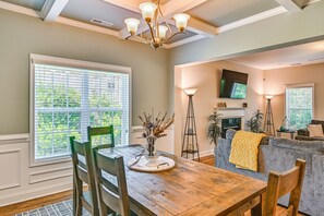 A dining area with a wooden table, chairs, a chandelier, and a window with blinds. - Stay & Play! Pinehurst Family & Group Golf Retreat (Pinehurst)