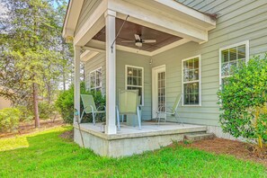 A covered porch with two chairs, a ceiling fan, and a small table. - Stay & Play! Pinehurst Family & Group Golf Retreat (Pinehurst)