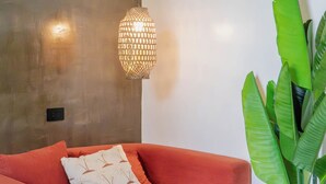Una camera moderna con un divano, una pianta in vaso e un lampadario a parete.