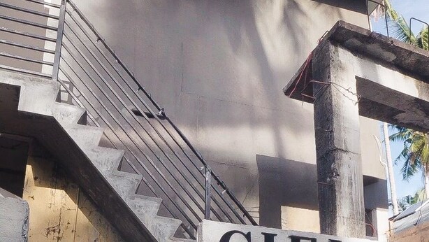 Un edificio moderno con una scala che conduce a un balcone, un cartello con scritto 'CIELO' e un po' di verde sullo sfondo.