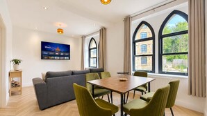 En moderne stue med sofa, spisebord, stole og et fjernsyn.