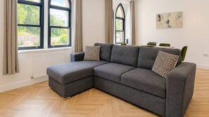 En moderne stue med en modulsofa, store vinduer og et spiseområde.