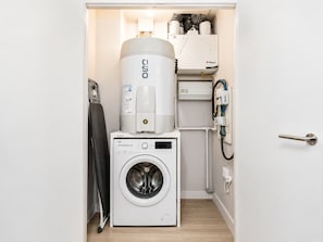 Ein kleiner Hauswirtschaftsraum mit Waschmaschine, Warmwasserbereiter und Wandheizung.
